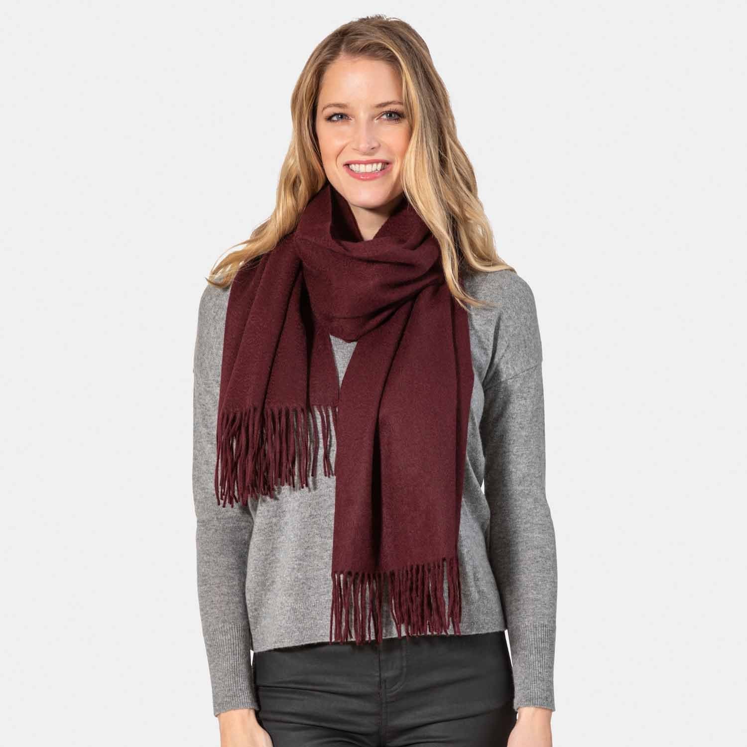 Picture of a woman wearing an oversized cashmere wrap with fringe, burgundy.