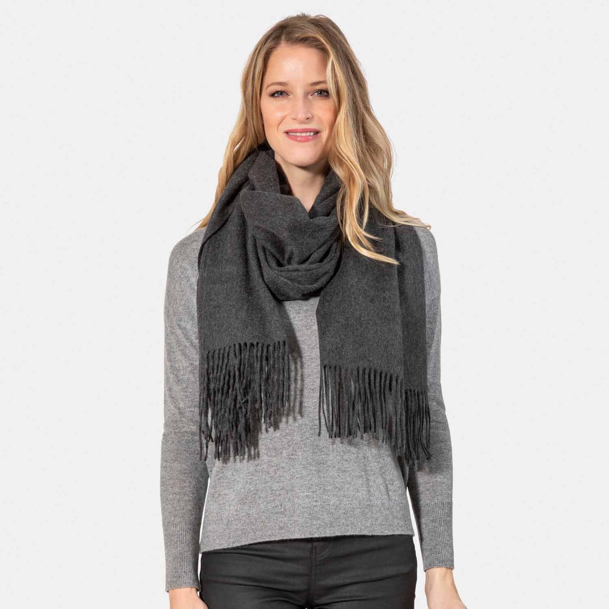 Picture of a woman wearing an oversized cashmere wrap with fringe, charcoal.