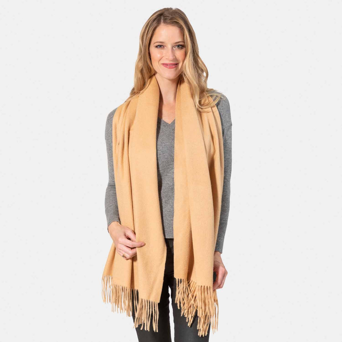 Picture of a woman wearing an oversized cashmere wrap with fringe, camel.