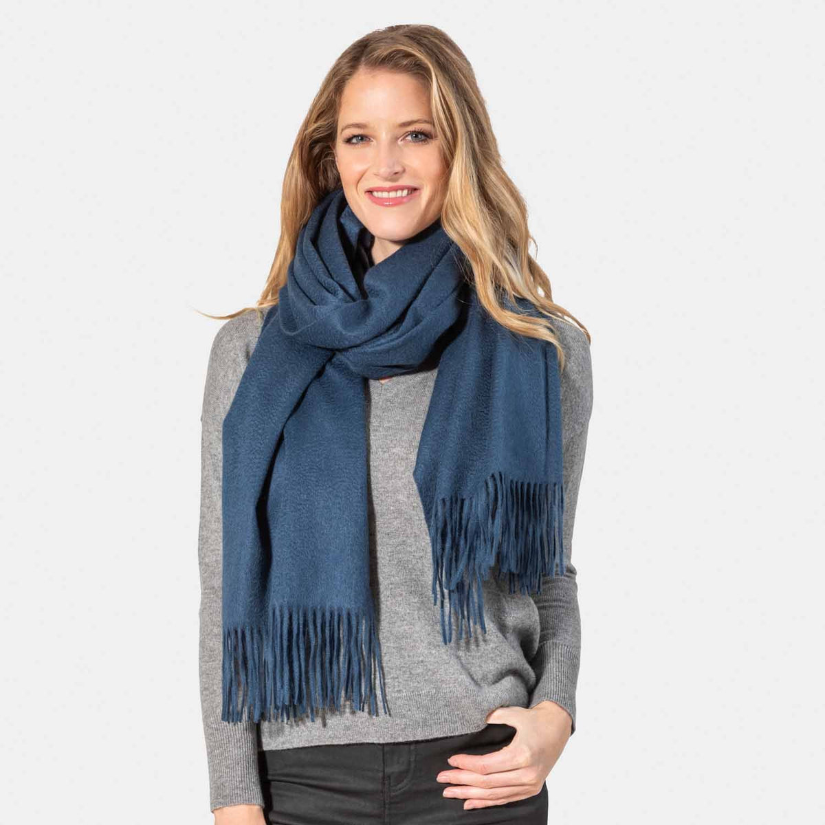 Picture of a woman wearing an oversized cashmere wrap with fringe, navy.