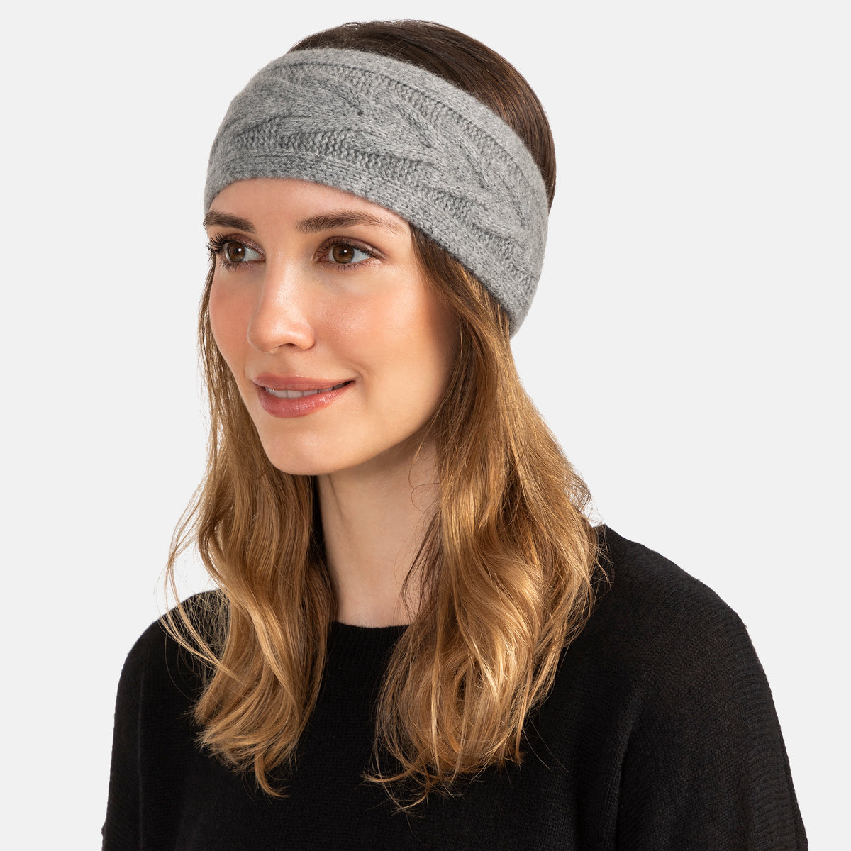 Picture of a woman wearing a knitted cashmere headband with a trellis cable design in Ivory.