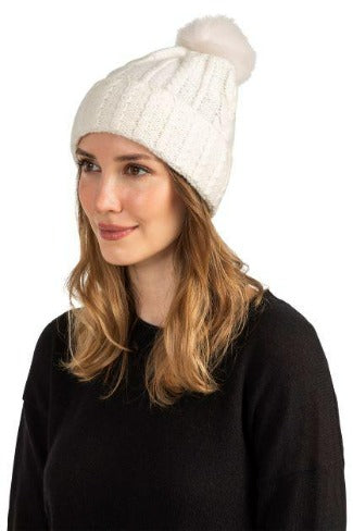 Woman wearing a gray cable knit cashmere hat with a shearling pom pom