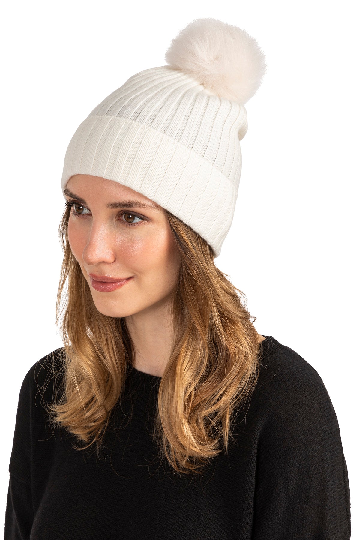 Woman wearing a camel color cashmere beanie with shearling pom, rib knit detail.