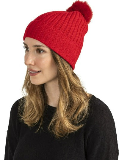 Woman wearing a black cashmere beanie with shearling pom, rib knit detail.
