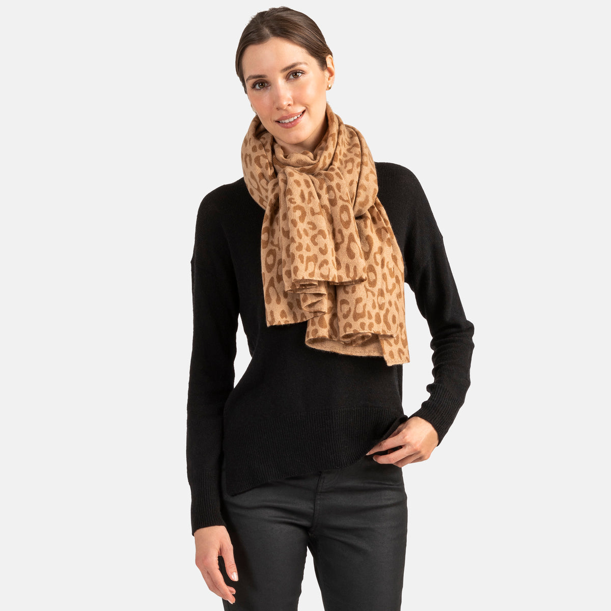 Picture of a woman wearing an oversized knitted cashmere travel wrap or scarf with a cheetah pattern in greycream and tan tones. tones.