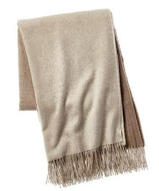 Picture of a woven wool and cashmere blend throw with twisted fringe, in a beige and cream ombre design.
