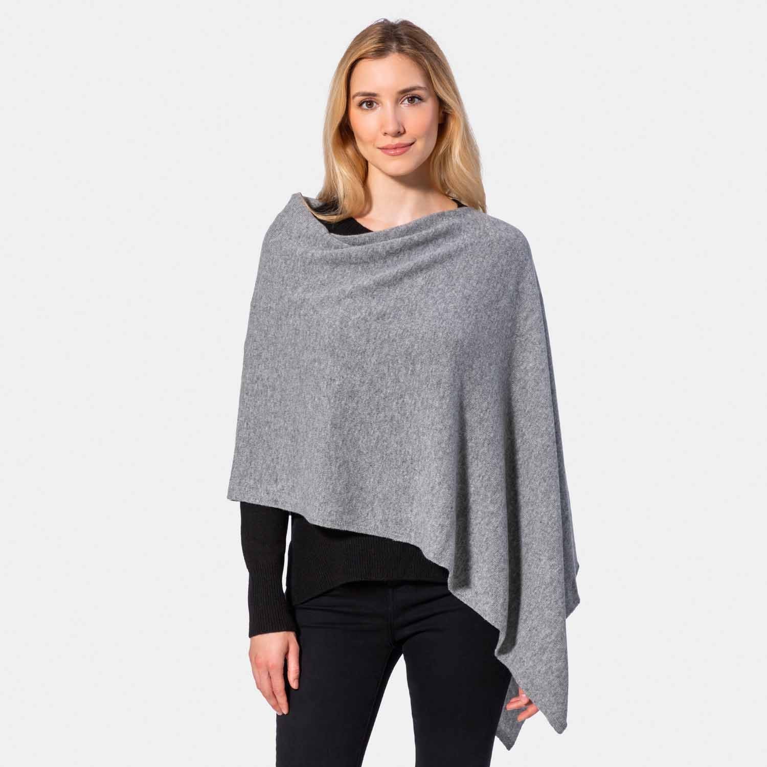 Picture of a woman wearing an asymmetrical ove the head poncho, black.