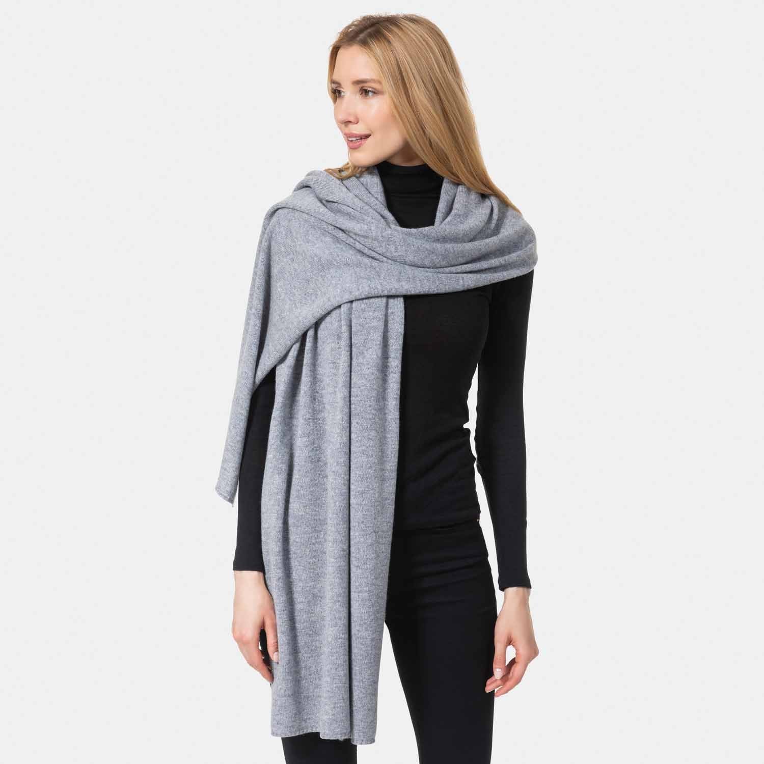 Picture of a woman wearing a grey cashmere jersey knitted oversize scarf or travel wrap.