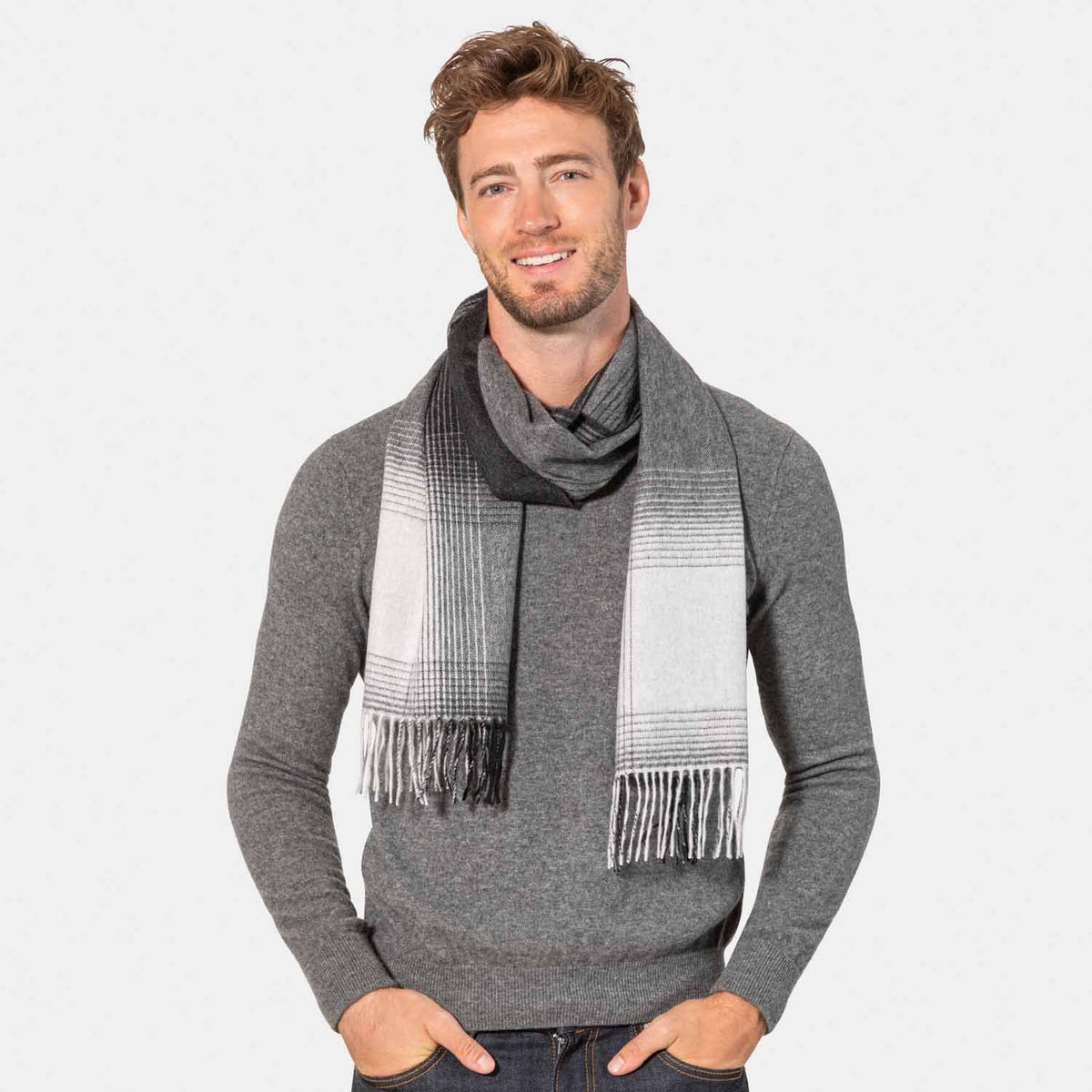 Picture of a man wearing an ombre cashmere scarf in grey and cream tones.