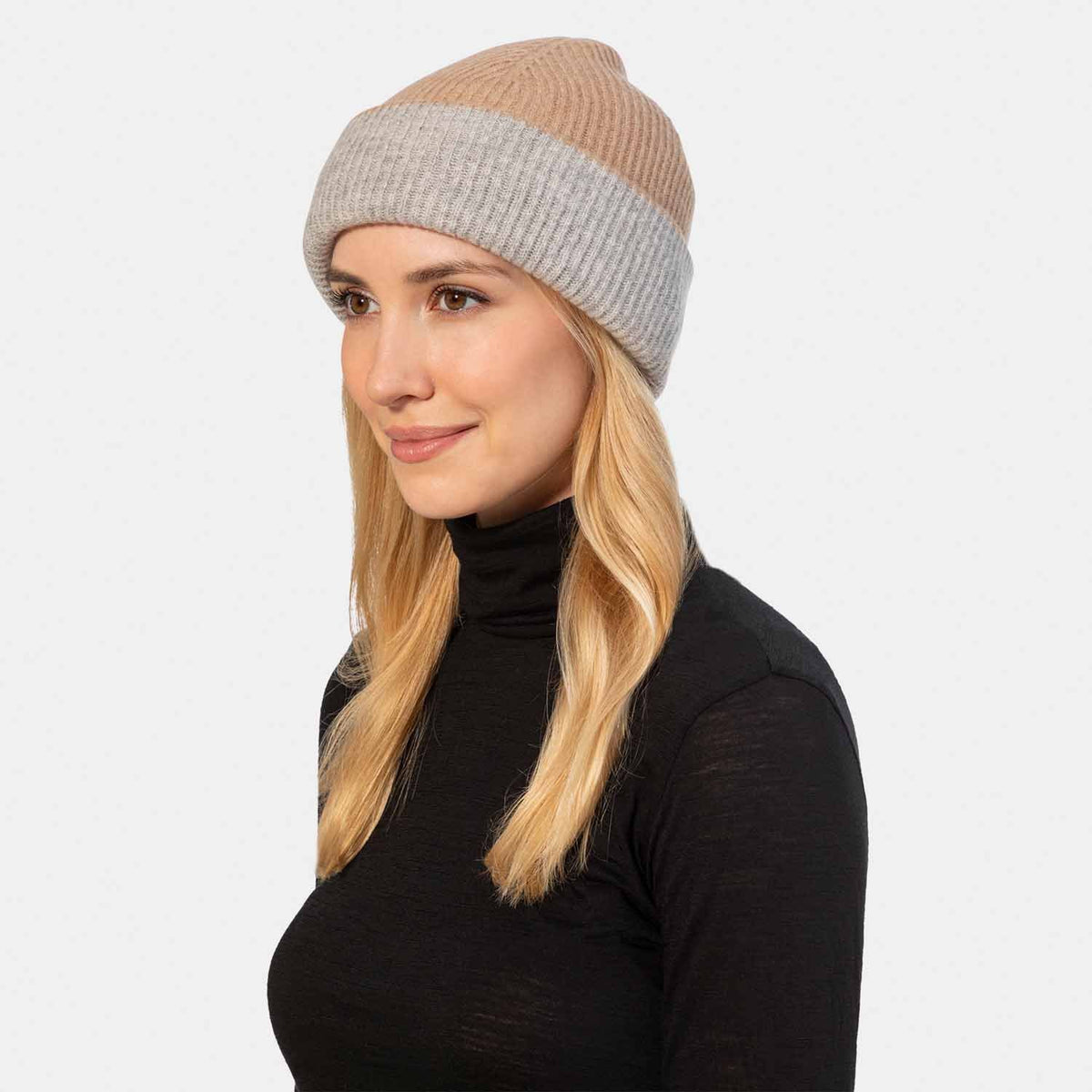 Picture of a woman in a reversible rib knit hat, grey and camel.