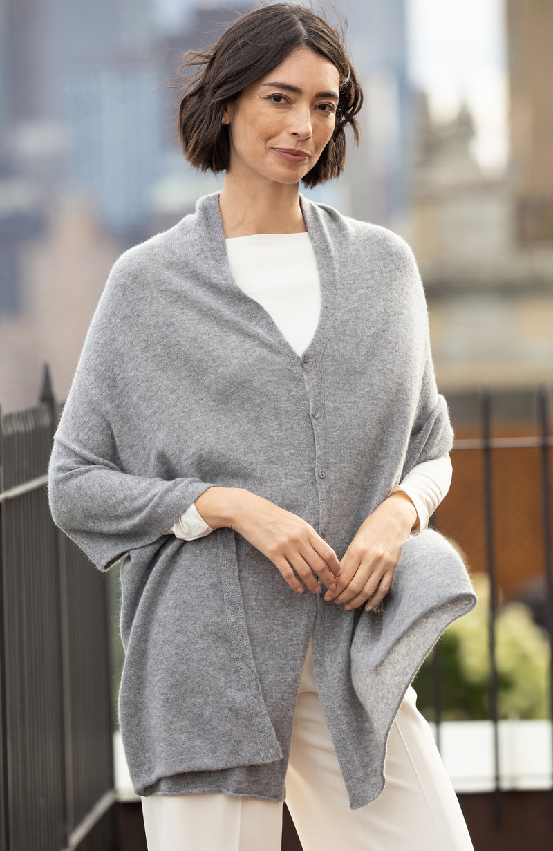 Woman wearing CASHMERE BUTTON SHOULDER PONCHO + WRAP in medium grey outdoors with blurred background