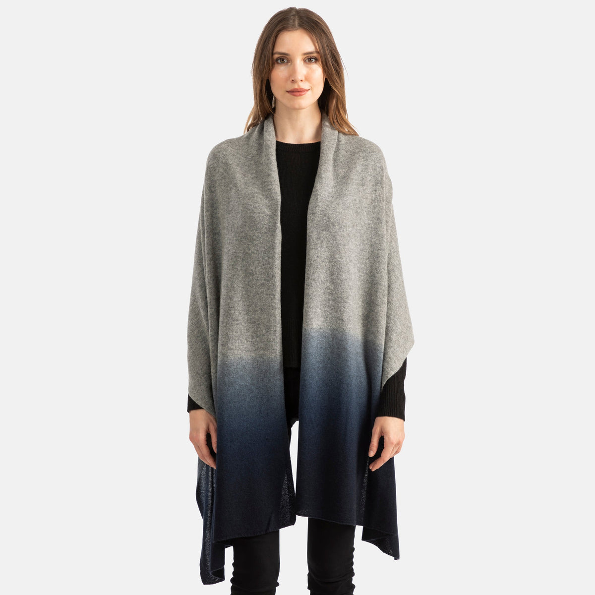 Picture of a woman wearing an oversized knitted cashmere travel wrap or scarf with an ombre pattern in dark green and black and burgundy.  [Grey/Navy]