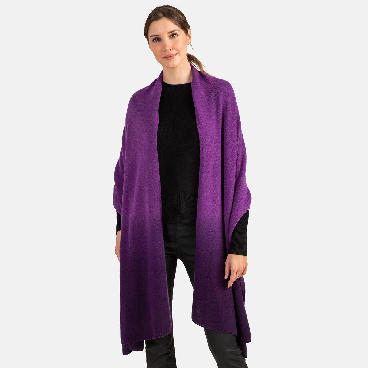 Picture of a woman wearing an oversized knitted cashmere travel wrap or scarf with an ombre pattern in grey and navy.  [Purple/Dark Purple]