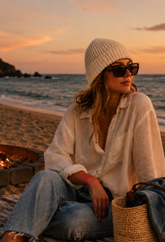 Woman wearing cashmere hat while sitting on a beach at sunset
