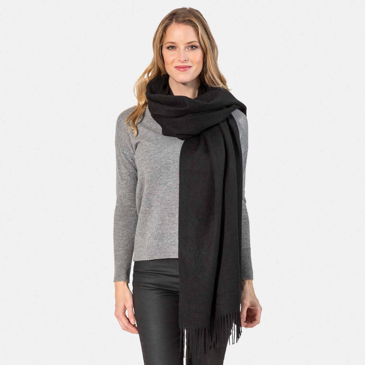 Picture of a woman wearing an oversized cashmere wrap with fringe, black.