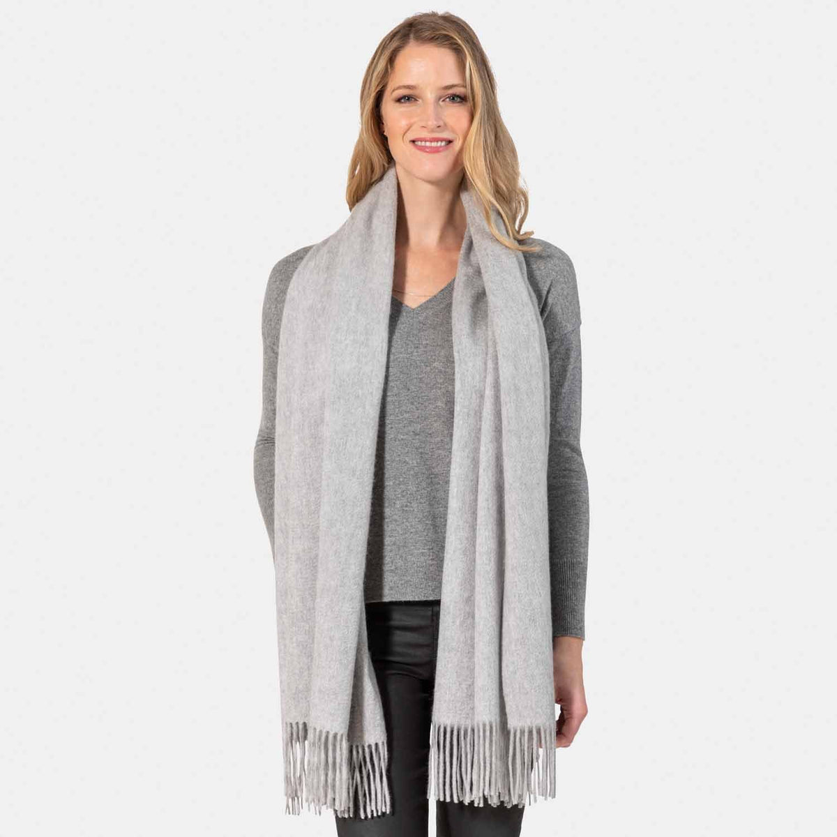 Picture of a woman wearing an oversized cashmere wrap with fringe, grey.