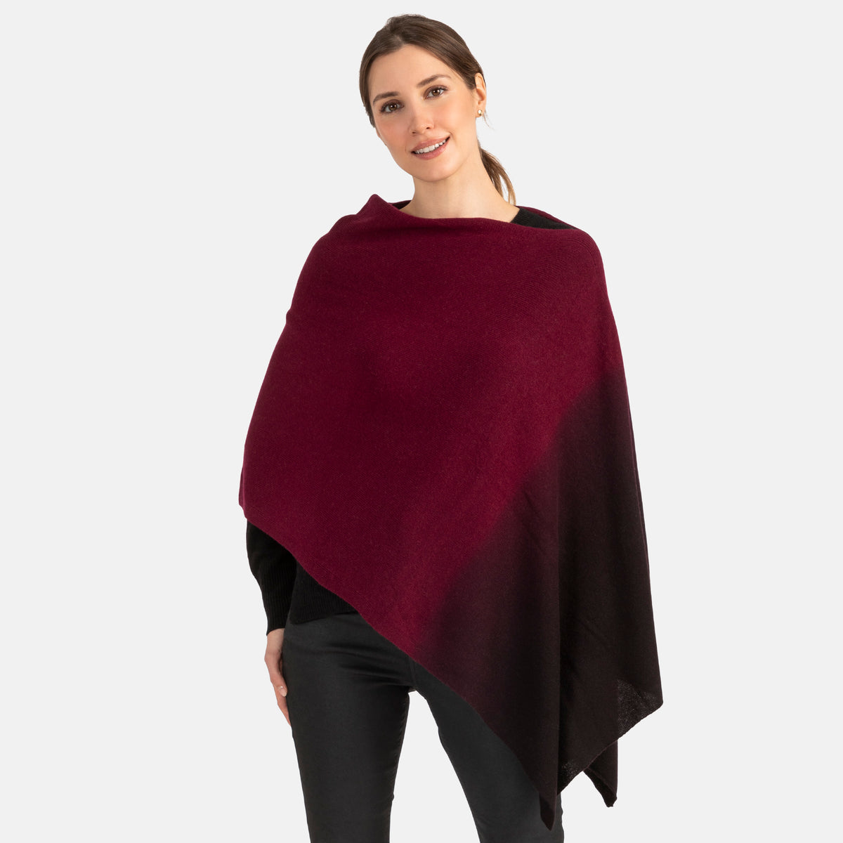 Picture of a woman wearing an assymetrical cashmere knit over the head poncho with dip dye patter in burgundy and black.