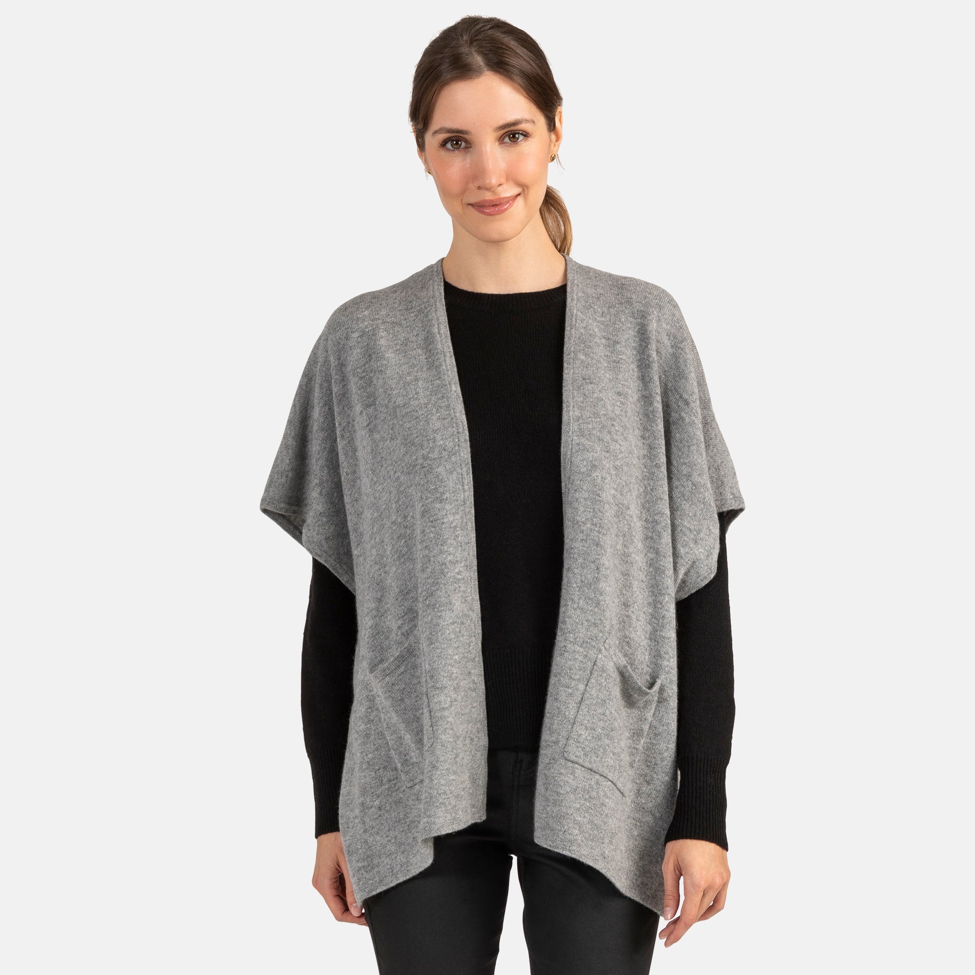 Picture of a woman wearing an open front knit cape with pockets in grey.