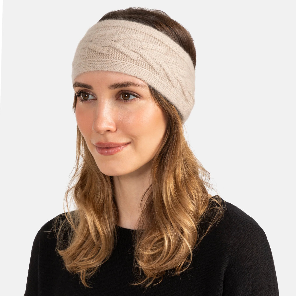 Picture of a woman wearing a knitted cashmere headband with a trellis cable design in soft pink.