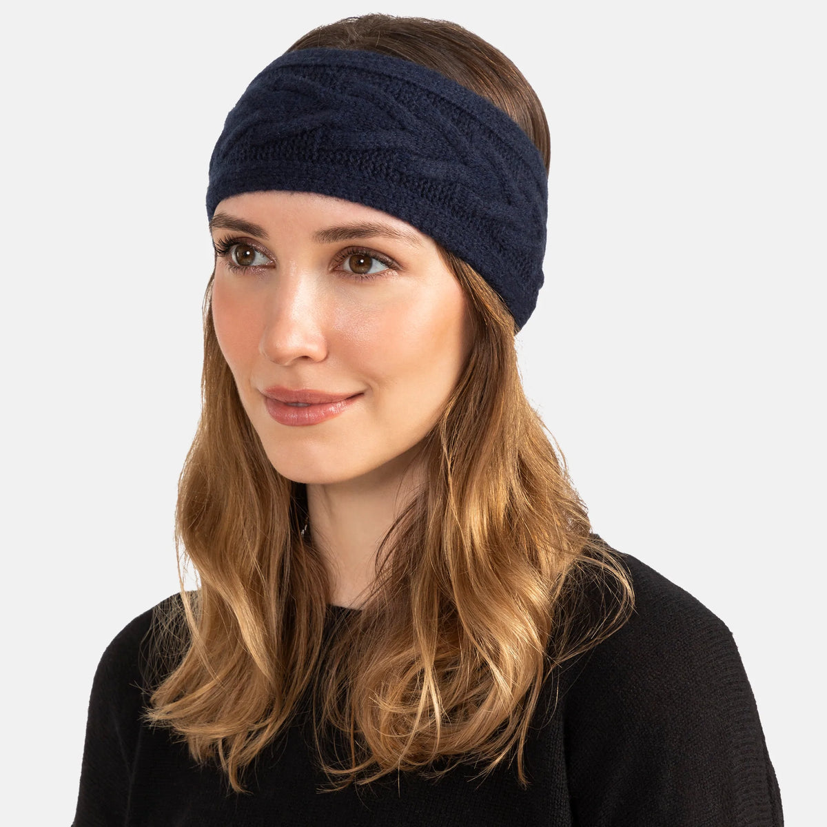 Picture of a woman wearing a knitted cashmere headband with a trellis cable design in soft pink.