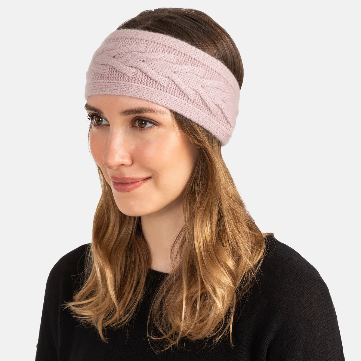 Picture of a woman wearing a knitted cashmere headband with a trellis cable design in soft pink.