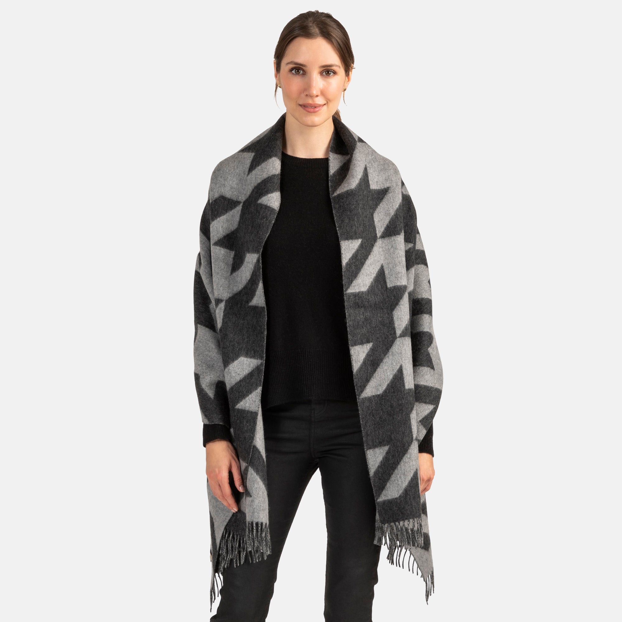 Picture of a woman wearing a large cashmere wrap with a houdstooth geometric pattern and fringe detail.