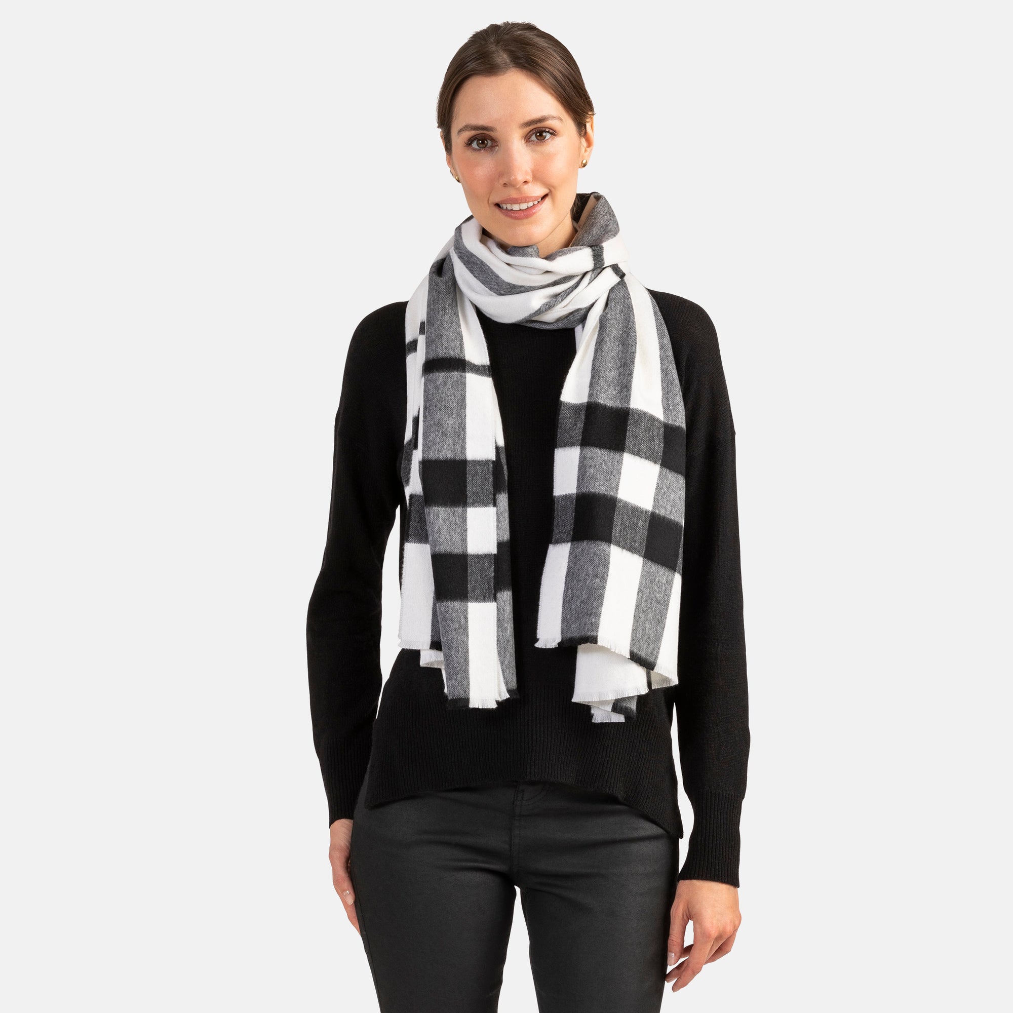 Picture of a woman in an oversized cashmere scarf with a black and white plaid design and fringe.