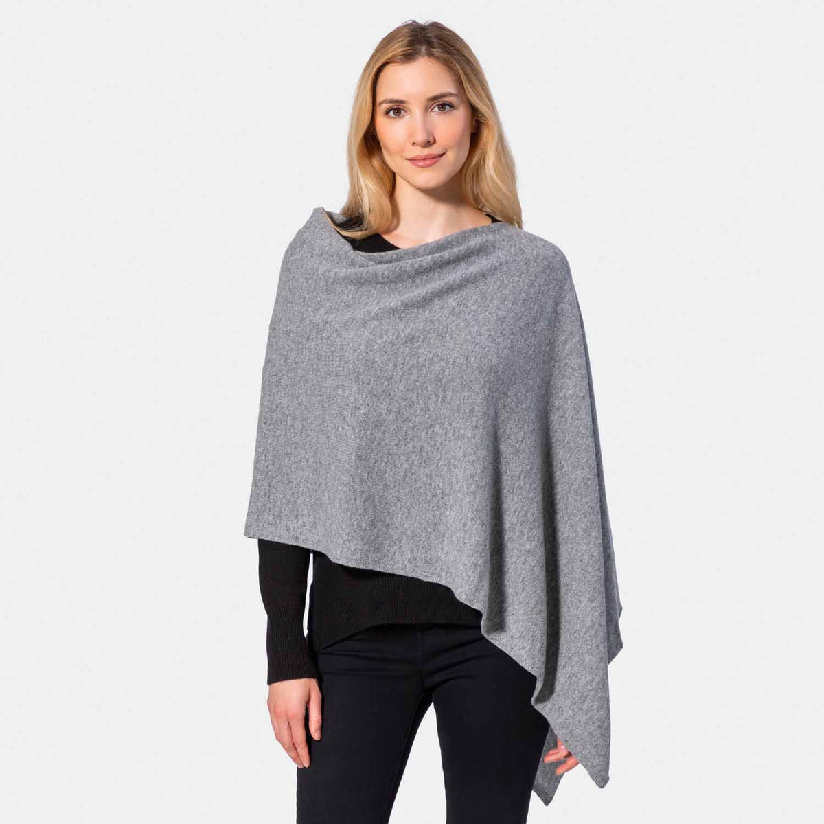 Picture of a woman wearing an asymmetrical ove the head poncho, grey.