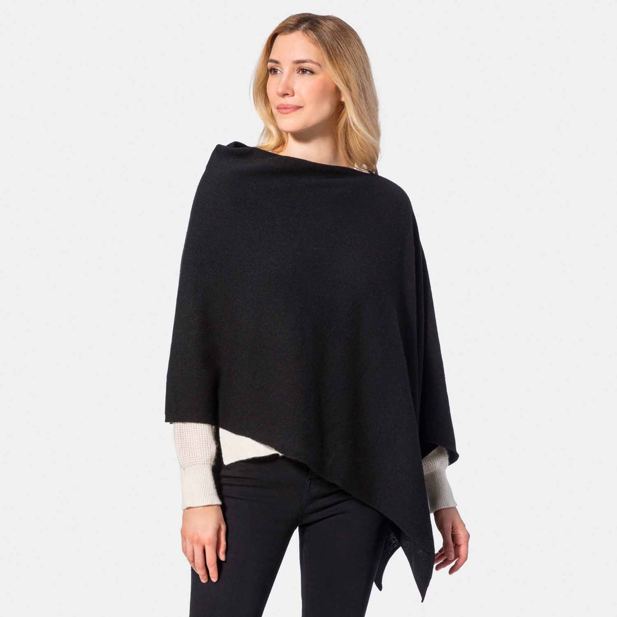 Picture of a woman wearing an asymmetrical ove the head poncho, black.