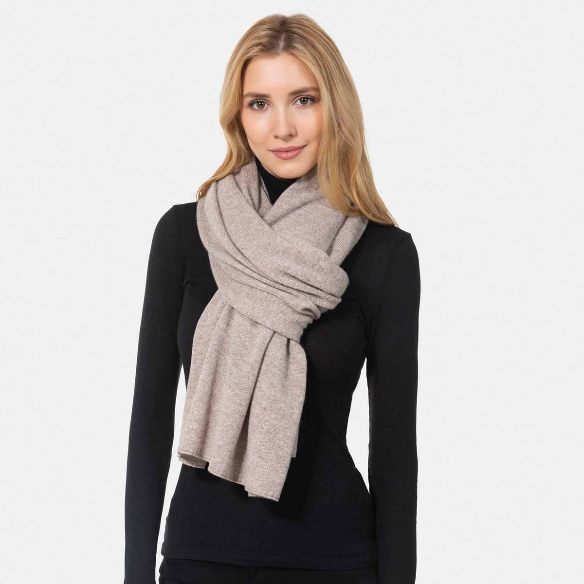 Picture of a woman wearing an oatmeal cashmere jersey knitted oversize scarf or travel wrap.