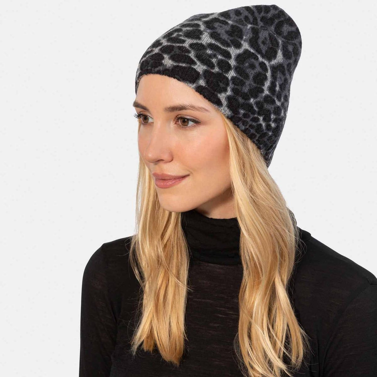 Picture of a woman wearing a leopard print cashmere beanie, gray and black.
