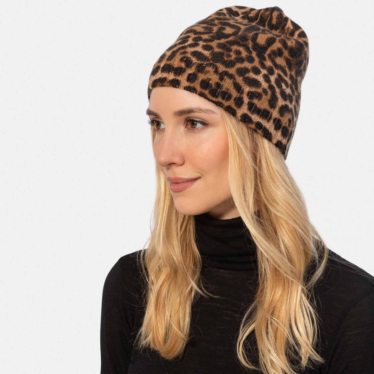 Picture of a woman wearing a leopard print cashmere beanie, tans and black.
