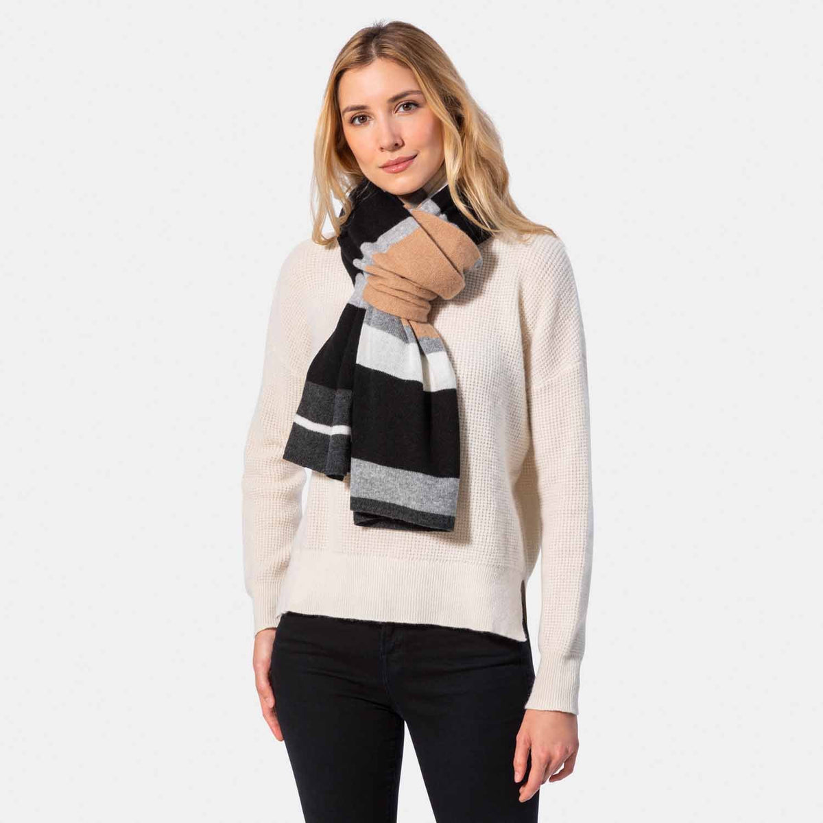 Picture of a woman in a colorblock knit travel wrap with camel, grey, cream and pink.