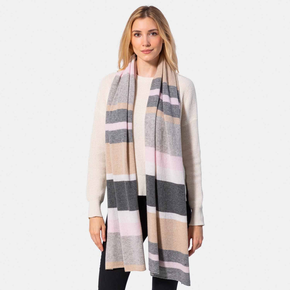 Picture of a woman in a colorblock knit travel wrap with camel, grey, cream and pink.