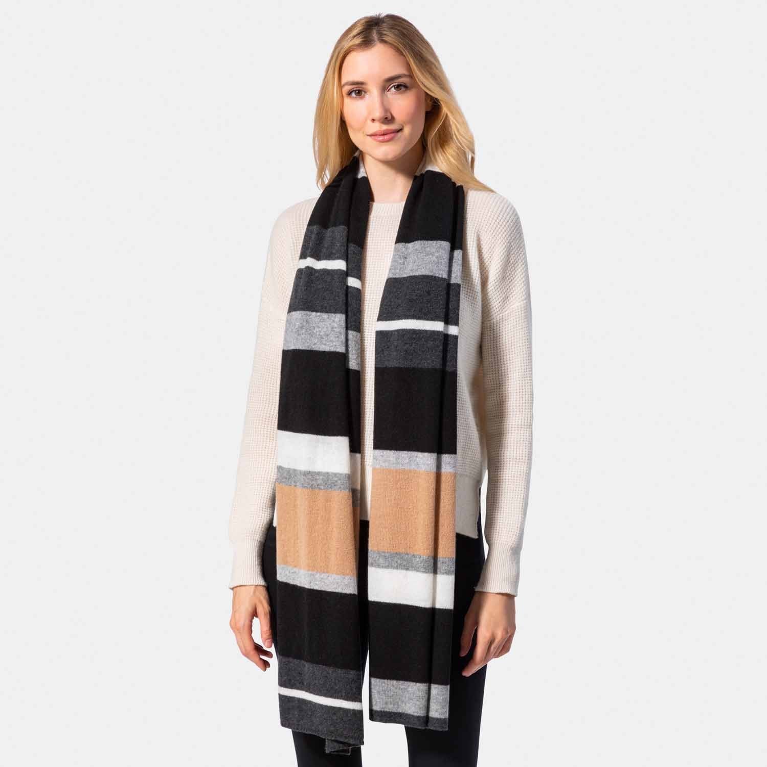 Picture of a woman in a colorblock knit travel wrap with camel, grey, cream and black.