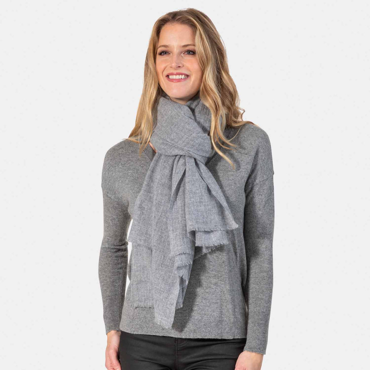 Picture of a woman wearing a lightweight gauzy cashmere wrap with eyelash fringe, grey.