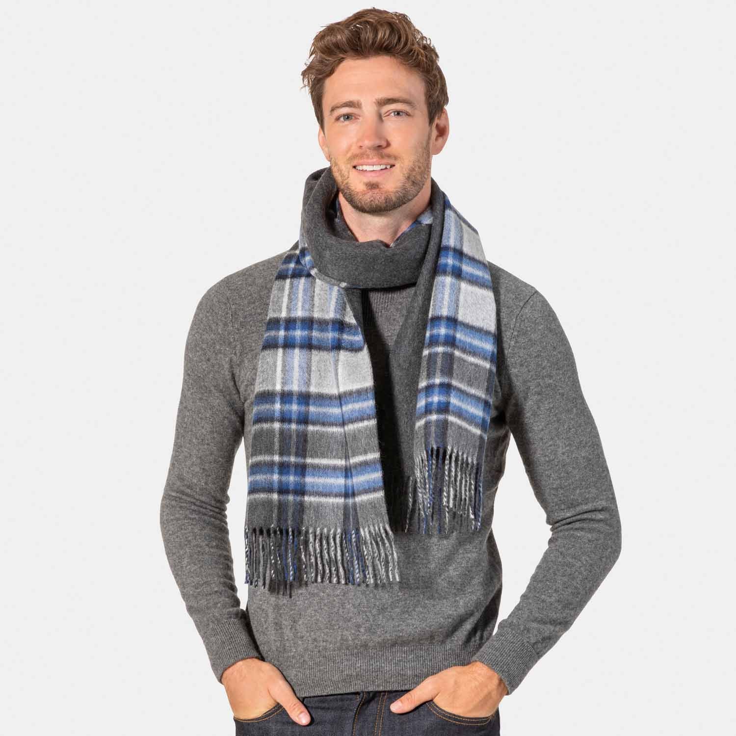 Picture of a man wearing a cashmere scarf with fringe in blue, grey and white plaid.