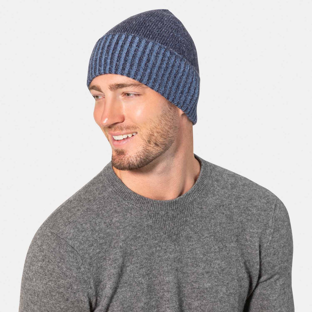Picture of a man wearing a plaited knit hat with contrast cuff in navy and lighter blue.