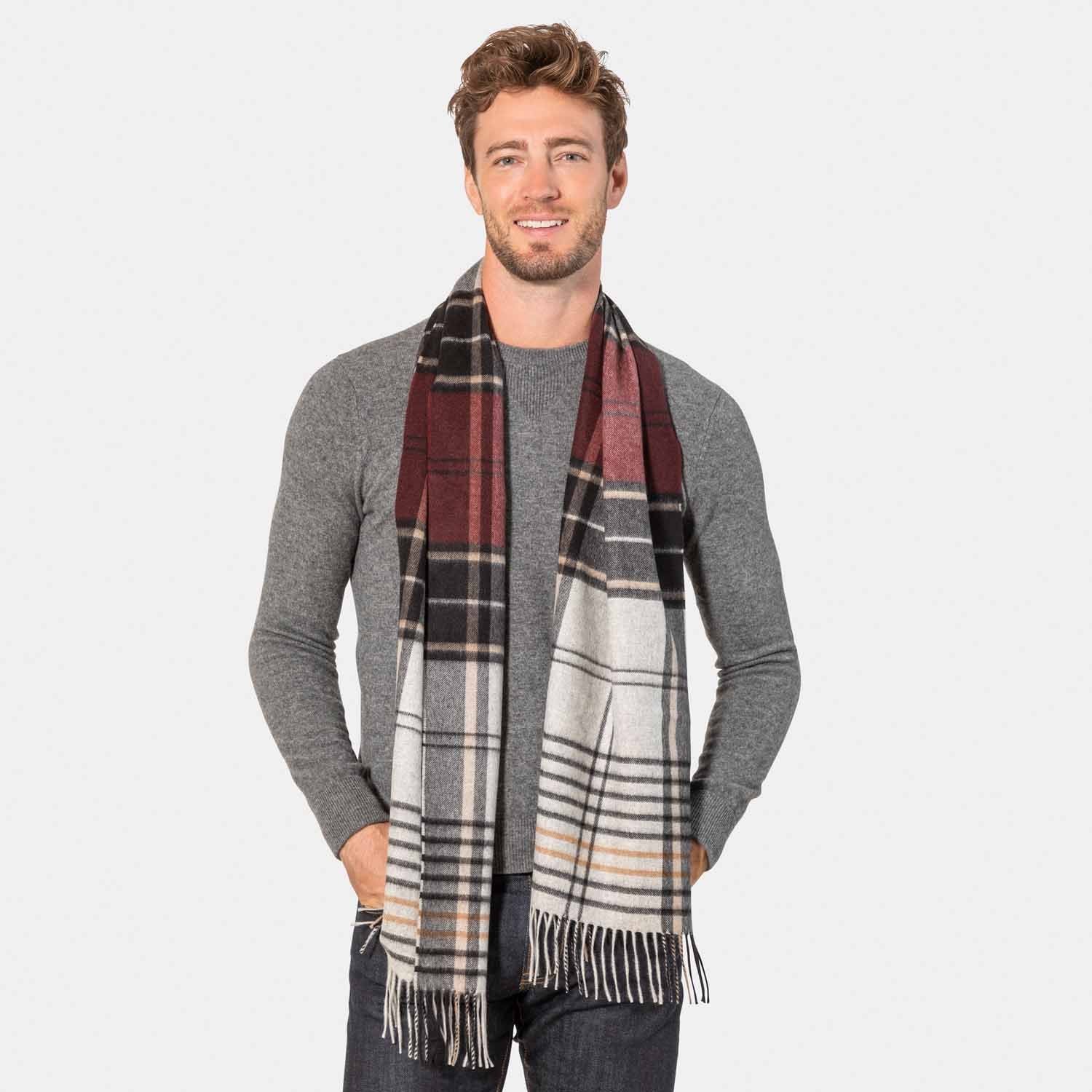 Picture of a man wearing an exploded plaid cashmere scarf with fringe  in burgundy, tans and black.