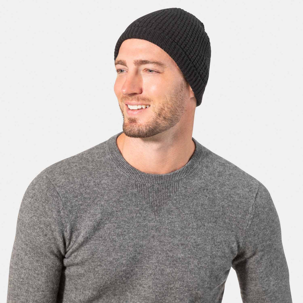 Picture of a man wearing a waffle knit cuffed hat in black.