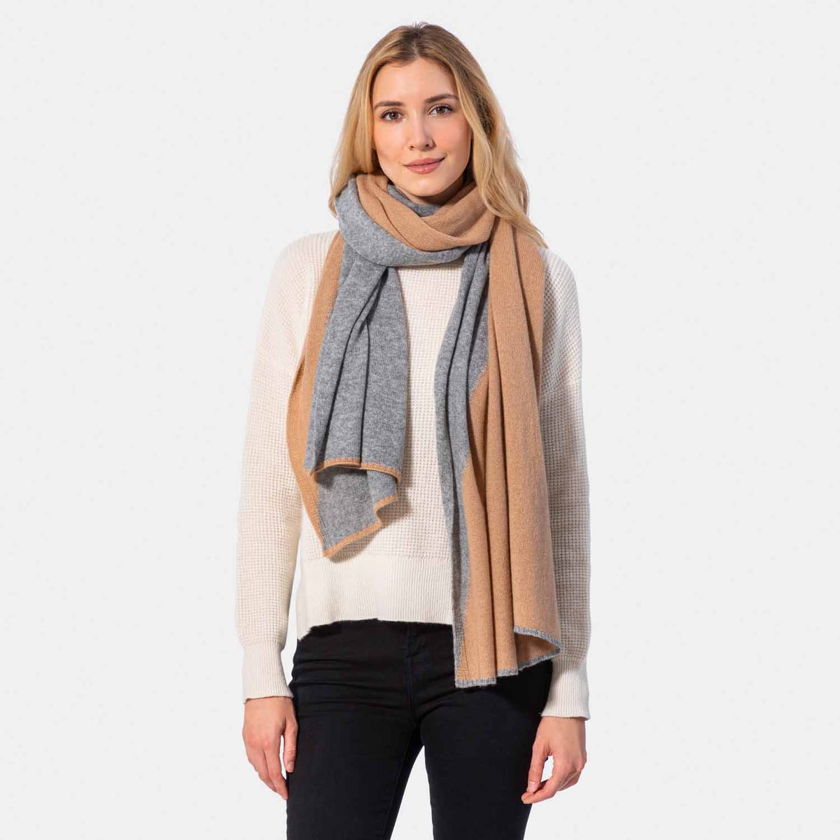 Picture of a woman in a two tone cashmere knit scarf, light grey and pink.
